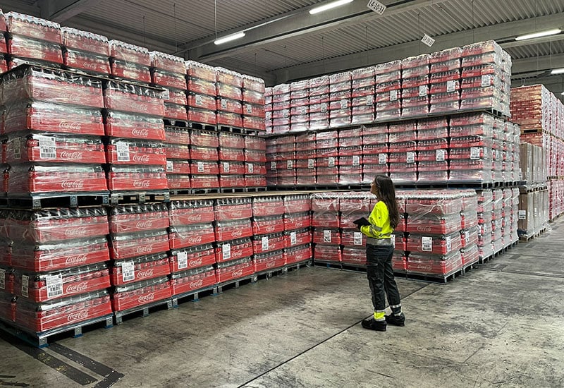 Karriere bei Coca-Cola: Anika vor einem zahlreichen Getränkepalettenndort Dorsten