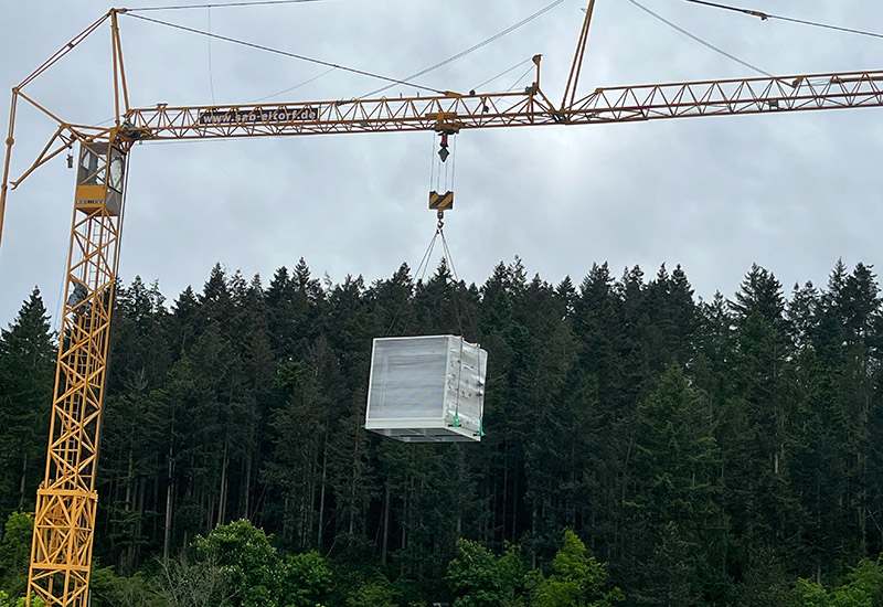 Kran hebt den Schaltschrank für die Coca-Cola Abfüllanlage über die Baustelle