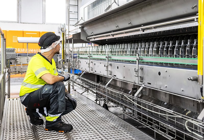 Coca-Cola Mitarbeitender in Deizisau prüft die Flaschen-Reinigungsmaschine